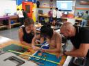 SITHS Engineering Teacher Everton Henriques, KD2ZZT (on the right), assists Olivia Wojtczak (on the left) and Ashley Li (in the middle) with buidling a directional antenna