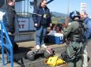 A Coast Guard Crew member briefs Jeff Underwood, KE7OUJ, Lauren OBrien, K7SXY, and Gary Mahan, N7IS regarding the helicopter flight from the Tillamook Airport to Camp Rilea. [Greg Sands, N1COM, Photo]